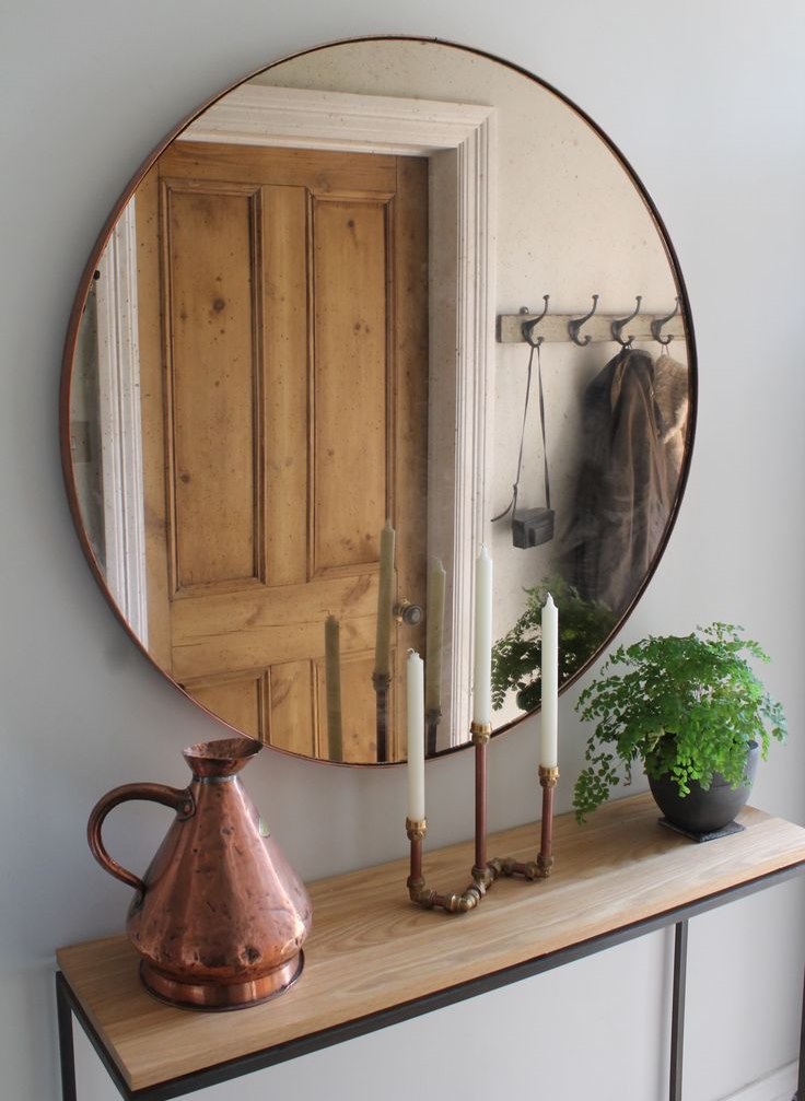 Круглое зеркало в тонкой раме напротив деревянной двери