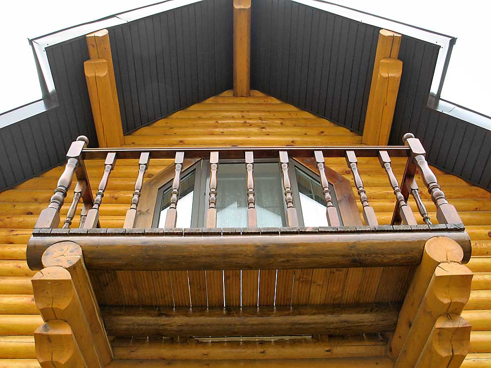 Открытый балкон на фасаде бревенчатого дома