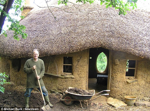 Michael Buck outside the cob house which he built for £150