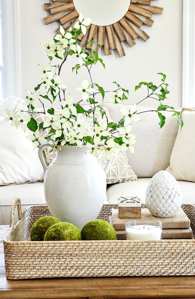 white urn on coffee table filled with white flowering dogwood branches 