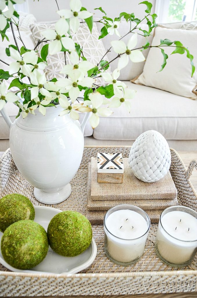 two large white candles in clear votives in a coffee table vignette